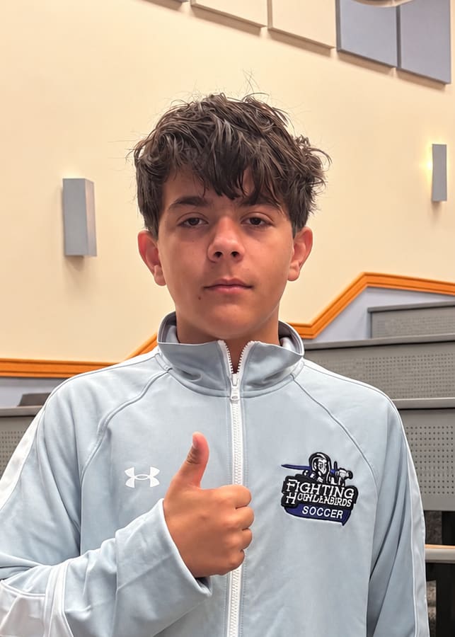 Brayden Bush in his Fighting Highlanderbirds soccer jacket, giving a thumbs up.